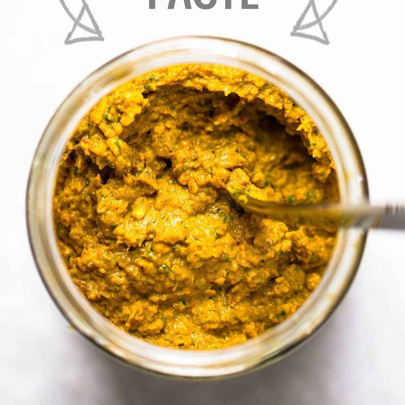 Homemade yellow curry paste in a jar with a spoon.