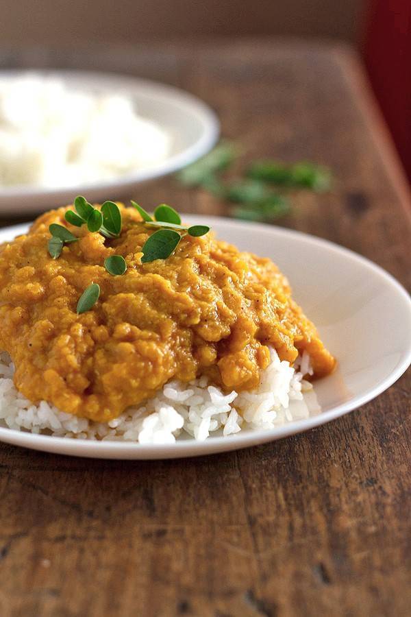Red lentil dhal with rice on a white plate.