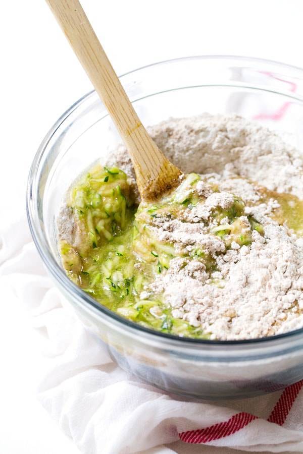 Muffin mix in a clear mixing bowl with a wooden spoon.