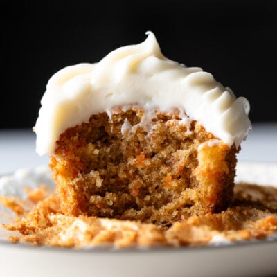 Carrot cake cupcake with cream cheese frosting on a plate.