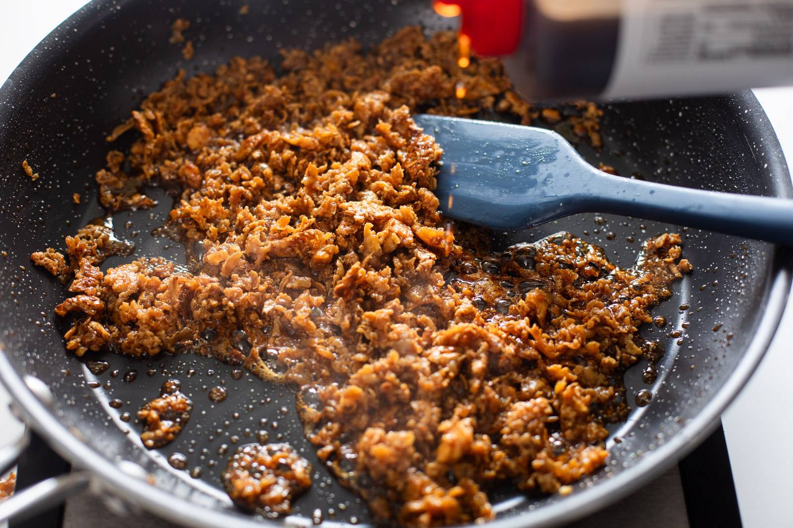 Adding teriyaki sauce to crumbled tofu.